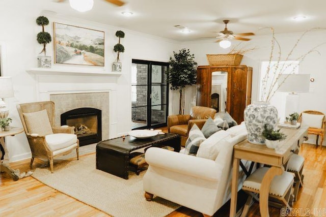 living area featuring ornamental molding, a fireplace, ceiling fan, and wood finished floors