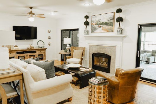 living area with wood finished floors, a ceiling fan, and a tile fireplace