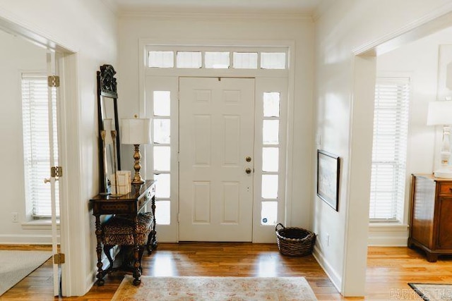 entryway with crown molding and light wood finished floors