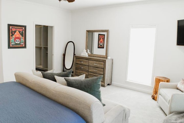 bedroom featuring light carpet, a spacious closet, ceiling fan, and crown molding