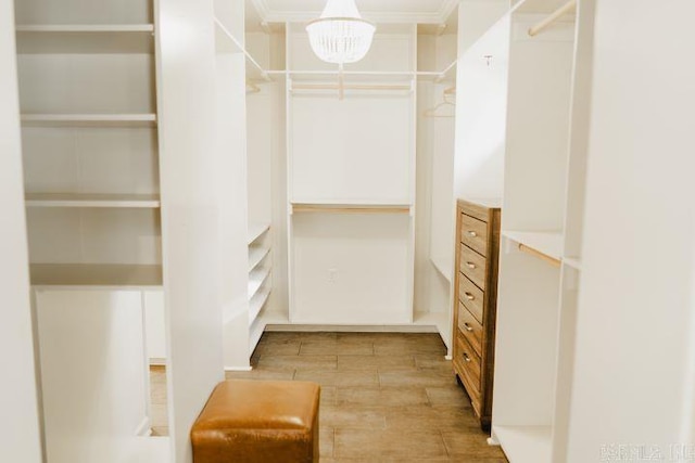 walk in closet with an inviting chandelier and light wood finished floors