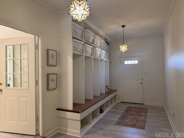 mudroom with baseboards, crown molding, and an inviting chandelier