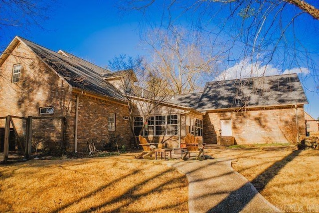 rear view of house featuring a yard and brick siding