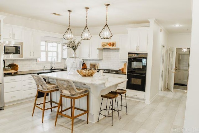 kitchen featuring a breakfast bar, a sink, ornamental molding, stainless steel appliances, and white cabinetry