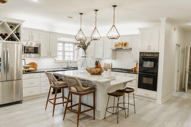 kitchen featuring a sink, appliances with stainless steel finishes, a breakfast bar area, and white cabinetry