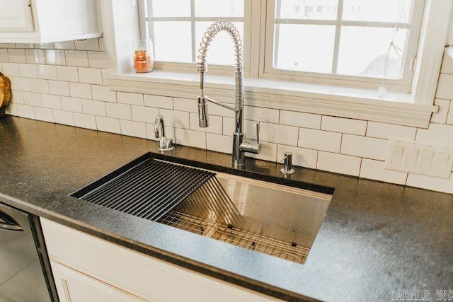 details featuring dark countertops, tasteful backsplash, a sink, white cabinets, and stainless steel dishwasher