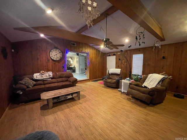 living room featuring visible vents, a ceiling fan, wood finished floors, wood walls, and vaulted ceiling with beams