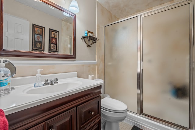 bathroom featuring wainscoting, toilet, a stall shower, and vanity