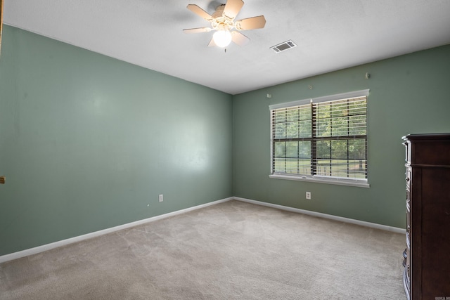 carpeted empty room with visible vents, a ceiling fan, and baseboards