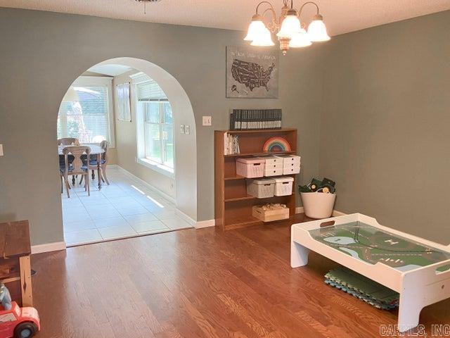 interior space featuring arched walkways, baseboards, an inviting chandelier, and wood finished floors