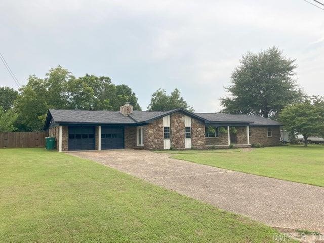 view of front of home featuring a front yard, an attached garage, a chimney, and dirt driveway