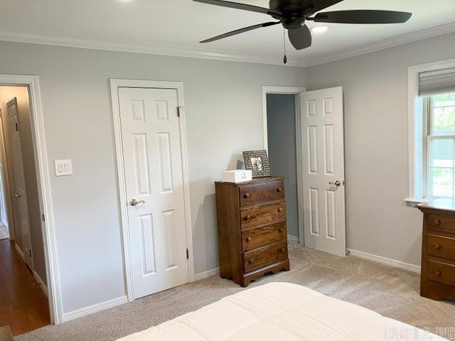 bedroom featuring baseboards, light colored carpet, ceiling fan, and crown molding