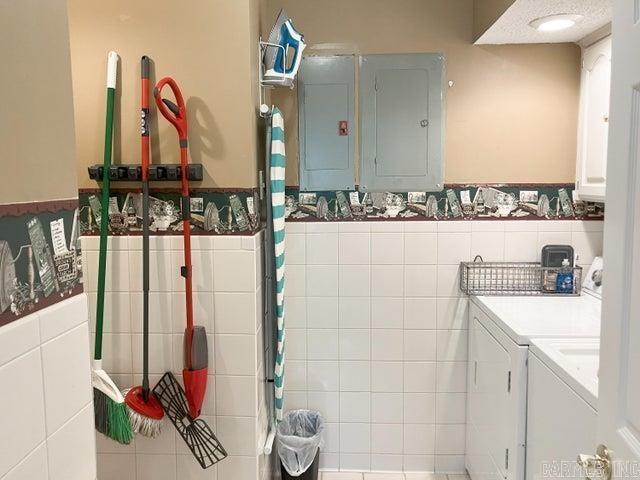 full bath featuring electric panel, tile walls, independent washer and dryer, and wainscoting