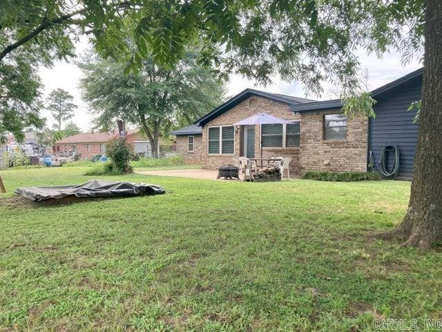 exterior space with a patio area, a lawn, and brick siding