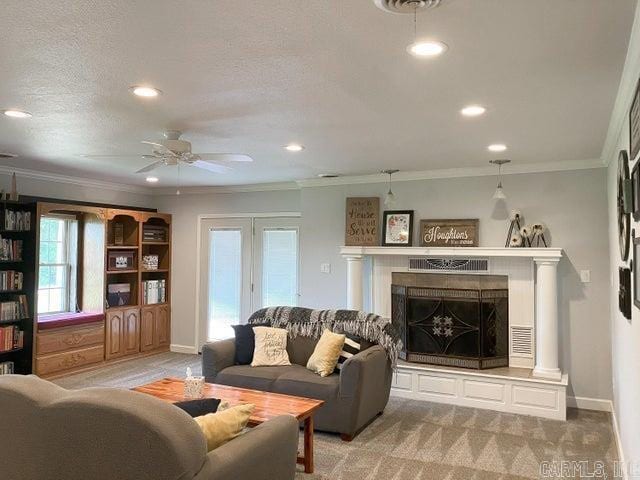 carpeted living room featuring a fireplace with raised hearth, baseboards, crown molding, and ceiling fan