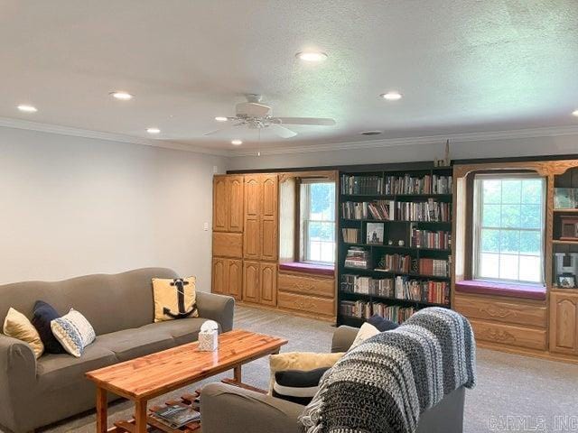 living room with ceiling fan, a textured ceiling, ornamental molding, and light carpet