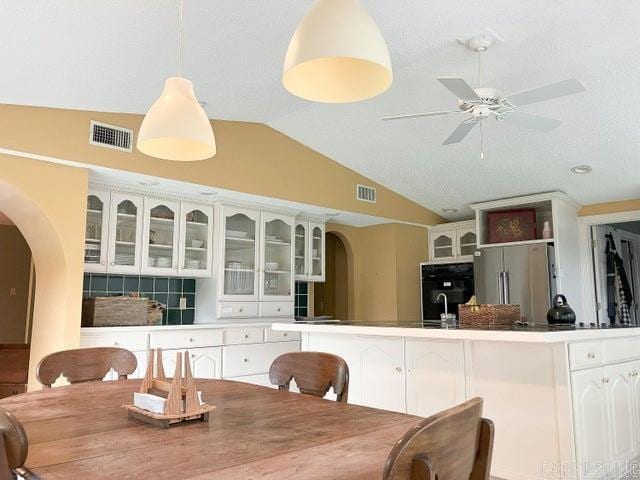 dining room featuring visible vents, arched walkways, a ceiling fan, and vaulted ceiling