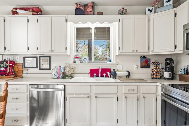 kitchen featuring a sink, stainless steel appliances, white cabinets, and light countertops