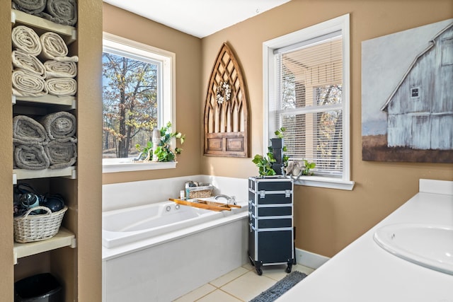 full bath featuring tile patterned floors, a garden tub, baseboards, and a sink