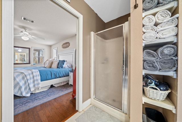 ensuite bathroom with wood finished floors, visible vents, a stall shower, and ensuite bathroom