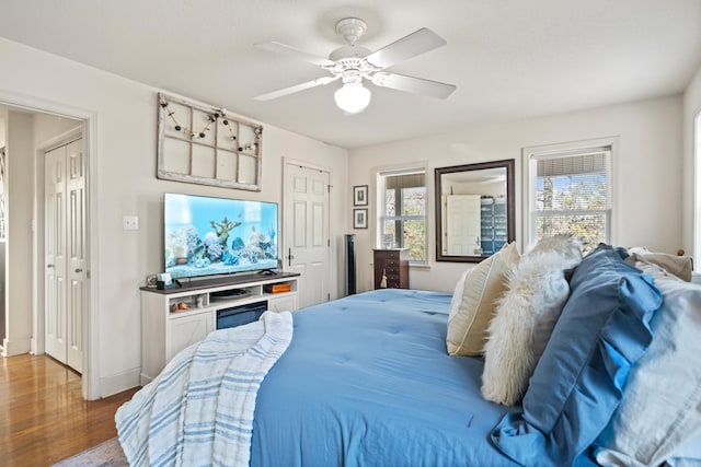 bedroom with ceiling fan, baseboards, and wood finished floors