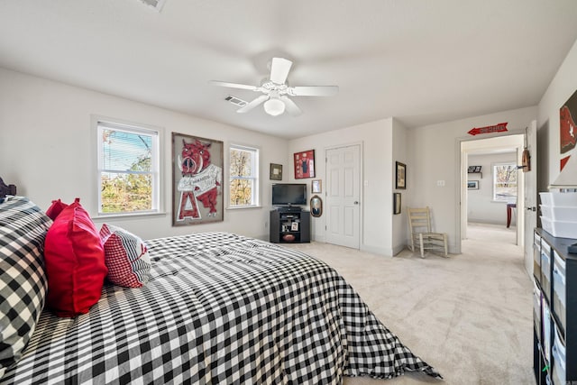 bedroom with baseboards, a ceiling fan, visible vents, and light carpet