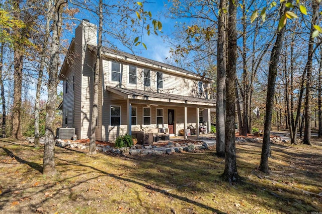 rear view of property featuring central air condition unit, a porch, a chimney, and a yard