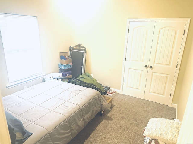 carpeted bedroom featuring baseboards and a closet