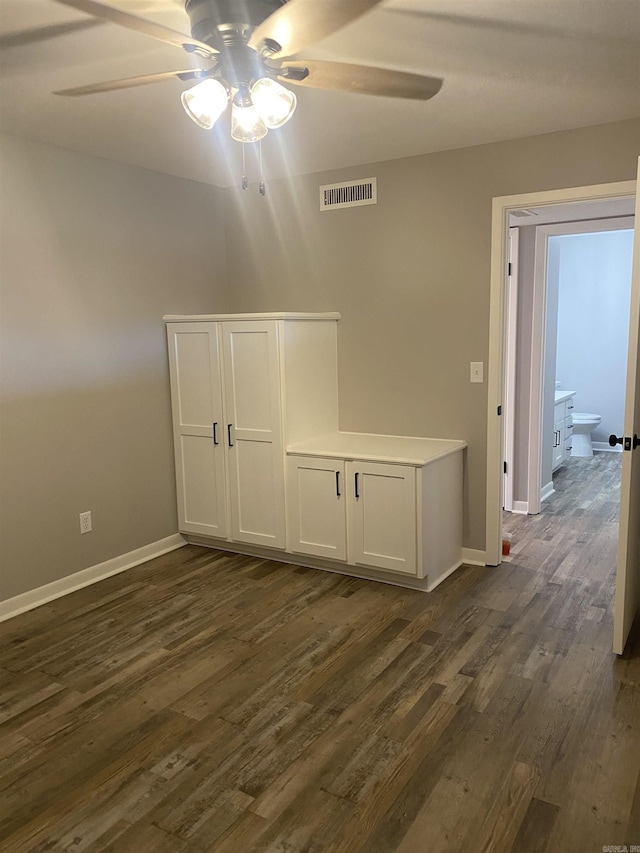 unfurnished room with visible vents, baseboards, dark wood-style flooring, and a ceiling fan