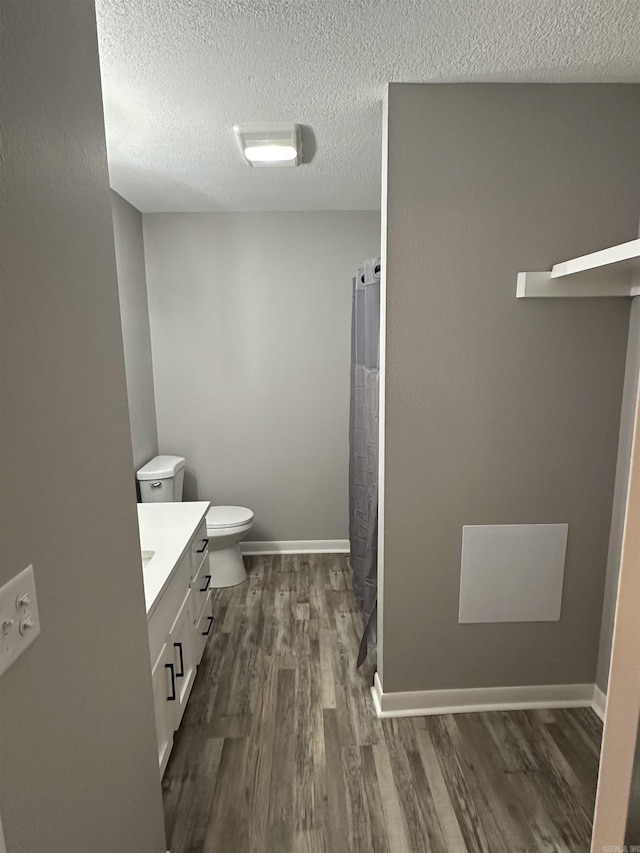 bathroom featuring vanity, wood finished floors, baseboards, a textured ceiling, and toilet