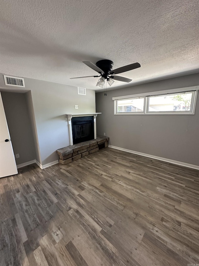 unfurnished living room with visible vents, wood finished floors, a stone fireplace, baseboards, and ceiling fan