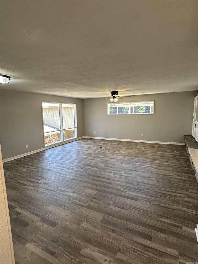 spare room featuring dark wood finished floors, ceiling fan, baseboards, and a textured ceiling