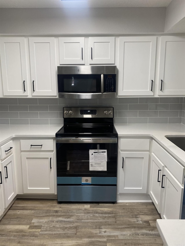 kitchen with tasteful backsplash, stainless steel microwave, electric range oven, and wood finished floors