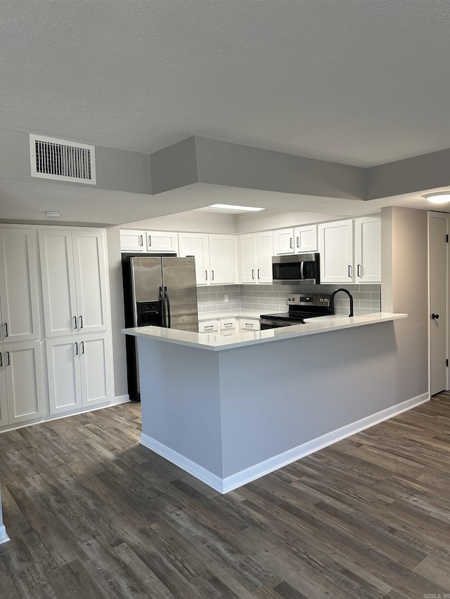 kitchen featuring visible vents, dark wood-type flooring, appliances with stainless steel finishes, and white cabinetry