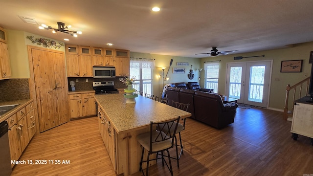 kitchen with visible vents, backsplash, a breakfast bar, light wood-style floors, and stainless steel appliances