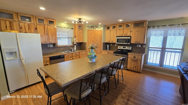 kitchen featuring a sink, stainless steel appliances, backsplash, and wood finished floors