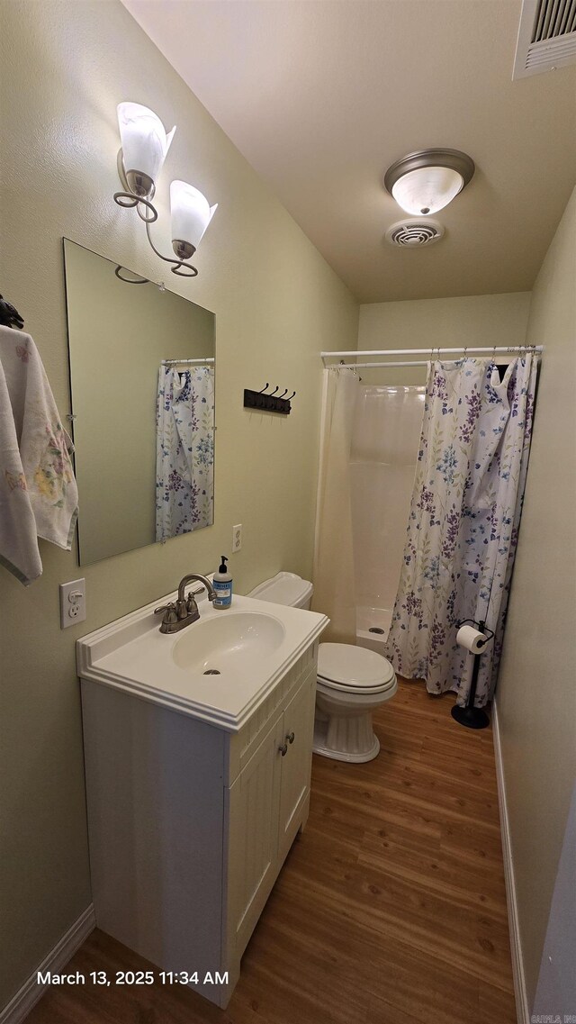 bathroom featuring vanity, toilet, wood finished floors, and visible vents