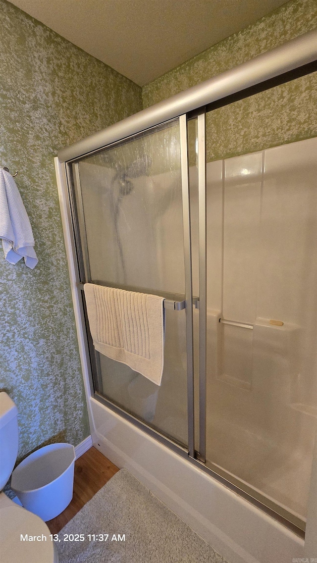 full bathroom featuring wallpapered walls, toilet, and wood finished floors