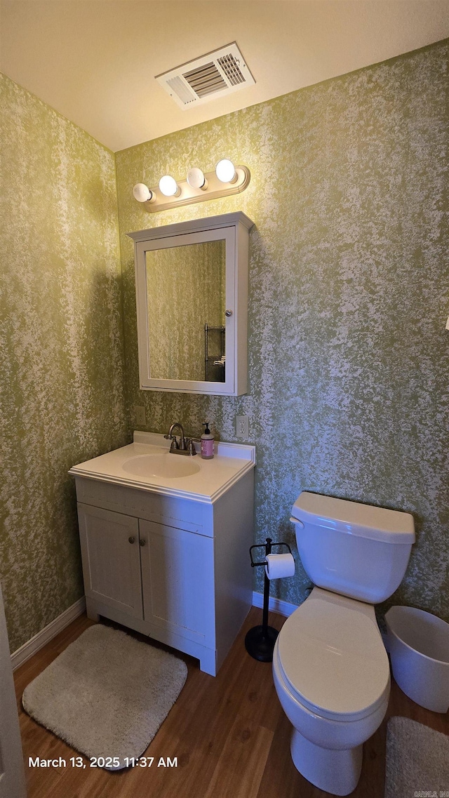 bathroom with vanity, toilet, wood finished floors, and visible vents