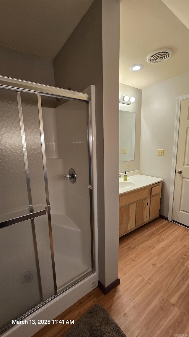 bathroom featuring a shower stall, wood finished floors, and visible vents