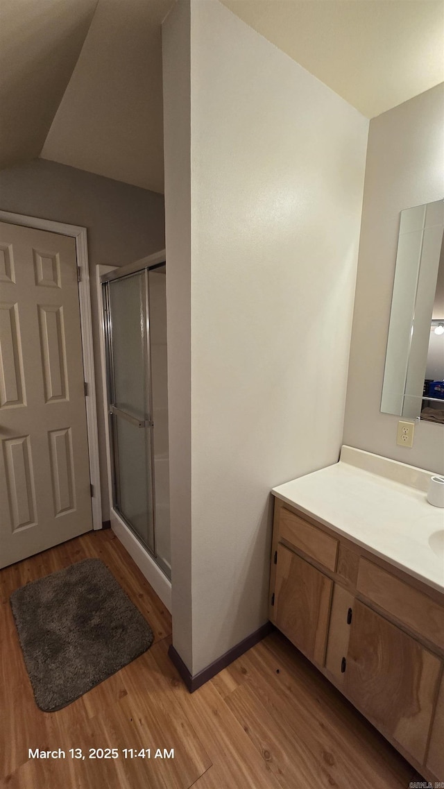 full bathroom with vanity, wood finished floors, a stall shower, and baseboards