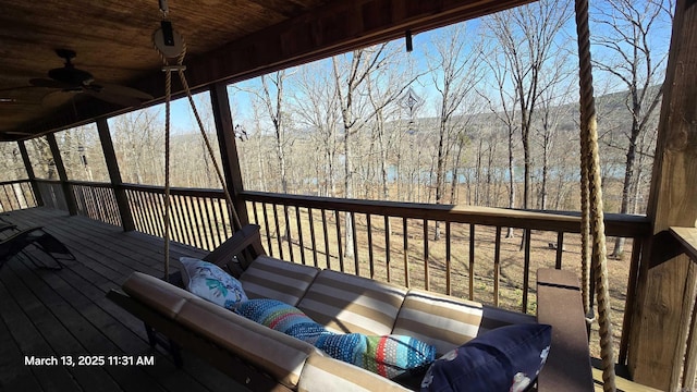 wooden terrace with an outdoor living space, a forest view, and ceiling fan