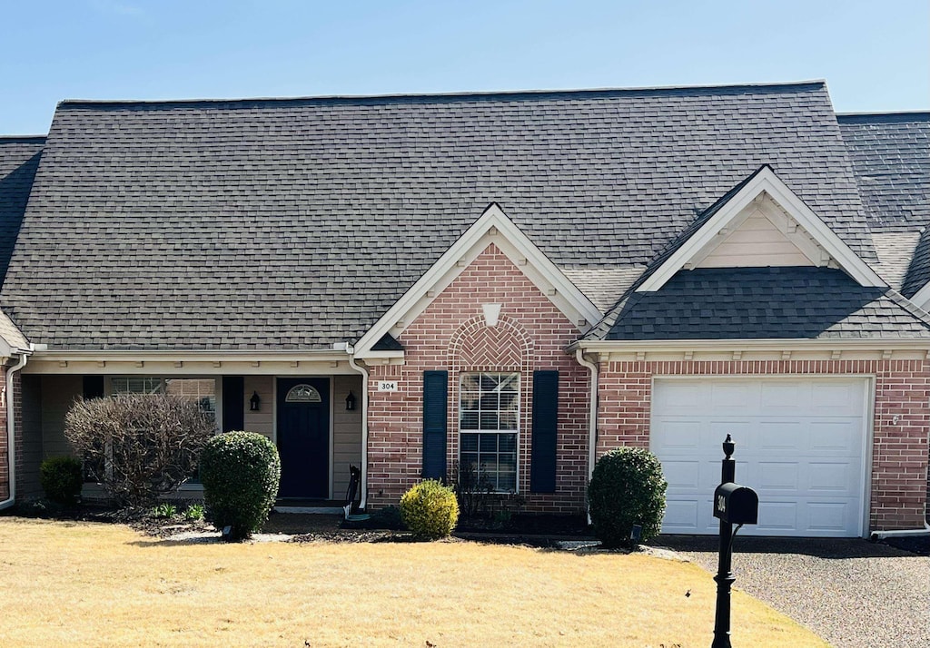 view of front of house featuring brick siding, driveway, a shingled roof, and a garage