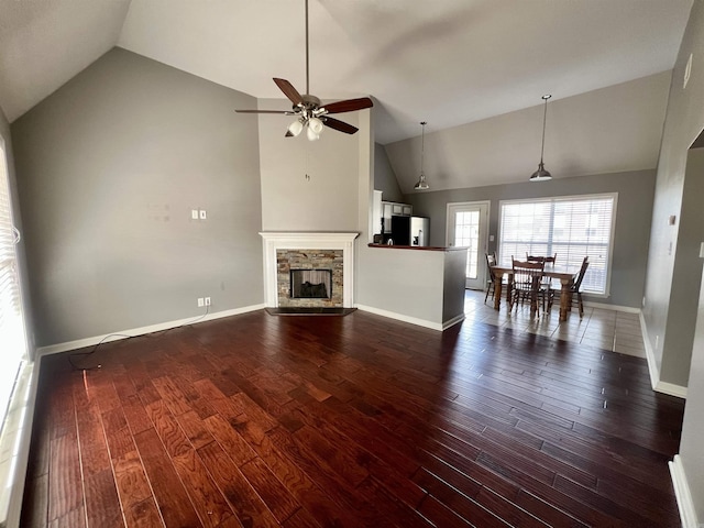 unfurnished living room featuring baseboards, dark wood finished floors, a fireplace, high vaulted ceiling, and a ceiling fan