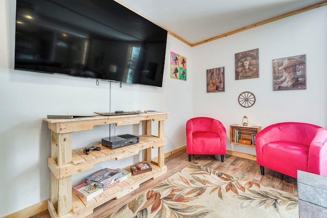 living area featuring baseboards, crown molding, and wood finished floors
