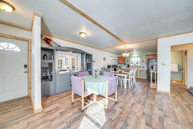 dining room featuring ornamental molding, baseboards, a notable chandelier, and light wood finished floors