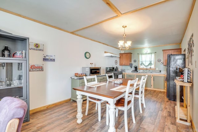 dining space with ornamental molding, light wood finished floors, baseboards, and a notable chandelier