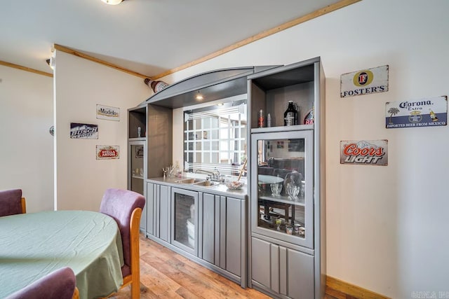 bar with crown molding, a sink, and light wood finished floors