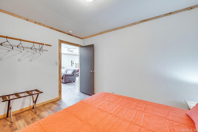 bedroom with baseboards, ornamental molding, and light wood finished floors