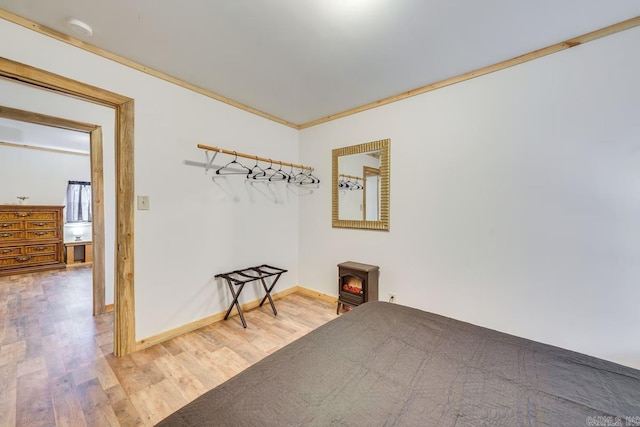 spare room featuring light wood-type flooring, crown molding, and baseboards